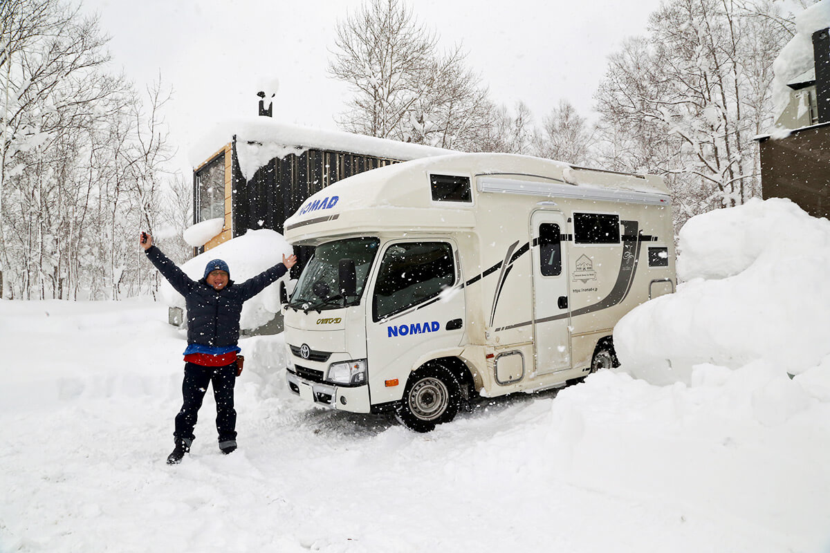 雪の中のキャンピングカーと岩田さん
